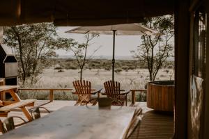 einen Tisch und Stühle auf einer Terrasse mit einem Sonnenschirm in der Unterkunft AfriCamps Waterberg in Vaalwater