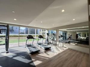 un gimnasio con equipo cardiovascular en un edificio con ventanas en Luxe Den-1BR Cozy Treat By Canal side, en Dubái