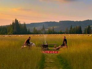 dos hombres sentados en un campo con una mesa de picnic en Szałas na szlaku en Witów