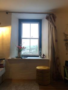 een raam in een kamer met een kruk en een vaas bij Gorgeous North Pembs Cottage in Saint Dogmaels