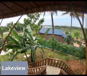 Vistas a una casa con 2 bancos de madera en Ratanakiri Lakeside Homestay & Tours en Banlung