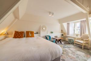 een slaapkamer met een groot wit bed en 2 stoelen bij LOT Hotel in Leiden