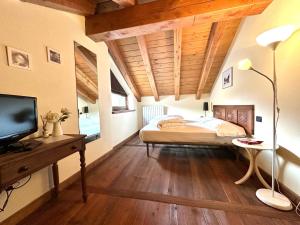 Schlafzimmer mit einem Bett und einem Schreibtisch mit einem TV in der Unterkunft Maison Rosset agriturismo, CAMERE, appartamenti e spa in Valle d'Aosta in Nus