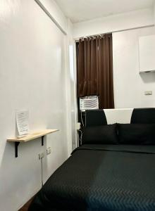 ein Schlafzimmer mit einem schwarzen Bett und einem Fenster in der Unterkunft Private room with AC and fan at EKG House Rental in Manila