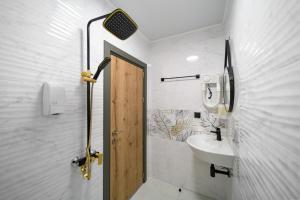 La salle de bains blanche est pourvue d'un lavabo et d'une douche. dans l'établissement Къщата, à Isperikh