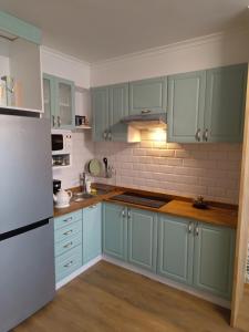 a kitchen with blue cabinets and a white refrigerator at Miętówka in Żywiec