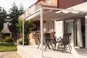 patio con tavolo e sedie sotto ombrellone di Apartmani Carmen a Bibinje (Bibigne)