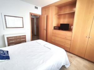 a bedroom with a white bed and wooden cabinets at Apartamento a 150m de la playa in Palamós