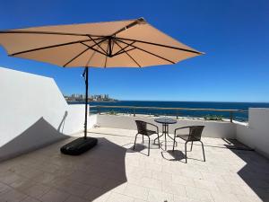 une terrasse avec une table, des chaises et un parasol dans l'établissement Moderno Depto Estudio frente a Playa Amarilla, à Concón
