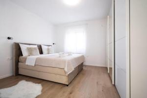 a white bedroom with a bed and a window at Apartmani Carmen in Bibinje