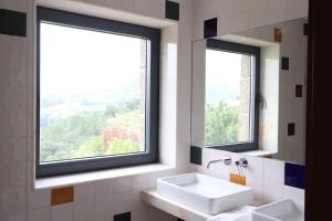 ein Badezimmer mit zwei Waschbecken und zwei Fenstern in der Unterkunft Quinta de Travanca - Casa do Páteo, Baião, Douro in Baião