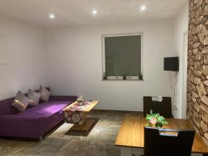 sala de estar con sofá púrpura y mesa en Sofa Apartment, en Seeheim-Jugenheim