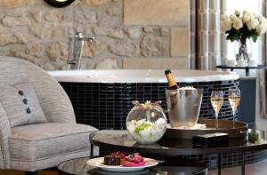 Domaine de la Klauss & Spa, Restaurant Gastronomique Le K في Montenach: غرفة مع زجاجة من الشمبانيا وطاولة مع كؤوس للنبيذ