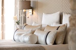 a pile of pillows on a bed in a bedroom at Domaine de la Klauss & Spa, Restaurant Gastronomique Le K in Montenach