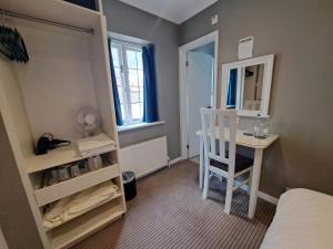 a small room with a bed and a desk and a mirror at The Thatch Inn in Gloucester