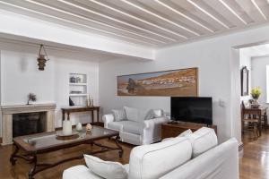 un soggiorno con mobili bianchi e TV di Androspremiumvillas ad Andro