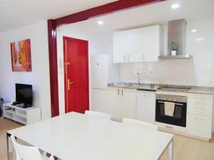 バレンシアにあるPrecioso piso en Cabanyal junto playa Las Arenasの白いキャビネットと赤いドア付きのキッチン