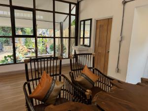 two chairs with pillows in a room with windows at Proud Chiang Mai Poshtel in Chiang Mai