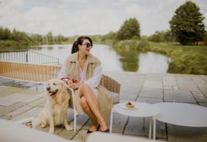 a woman sitting on a bench with a dog at Pałac Pakoszów Schlosshotel Wernersdorf in Jelenia Góra