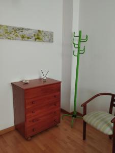 um quarto com uma cómoda, uma cadeira e um poste verde em Acogedor Apartamento En Huesca em Huesca