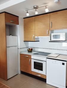 a kitchen with white appliances and wooden cabinets at Acogedor Apartamento En Huesca in Huesca