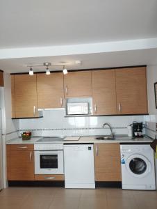 a kitchen with white appliances and wooden cabinets at Acogedor Apartamento En Huesca in Huesca