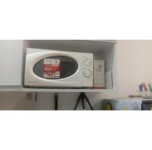 a white microwave sitting on a shelf in a kitchen at Homey Studio Condo by Malou in Calamba