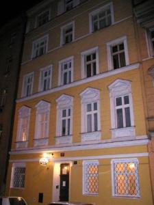 ein großes gelbes Gebäude mit weißen Fenstern auf einer Straße in der Unterkunft Pension Prague City in Prag