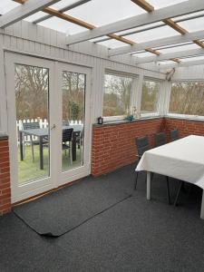 a screened in patio with a table and chairs at Søhusets anneks2 in Viborg