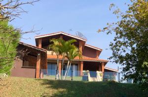 a house with a palm tree in front of it at CHACARA THA&THI COND FECHADO WI FI SPA e PISC AQUECECIMENTO SOLAR in Bom Jesus dos Perdões