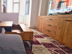 ein Wohnzimmer mit einem TV und einer Holzkommode in der Unterkunft Cozy Apartment Central II in Bacău