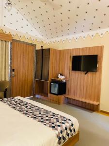 a bedroom with a bed and a tv on a wall at Nightingales Resort in Nāthdwāra