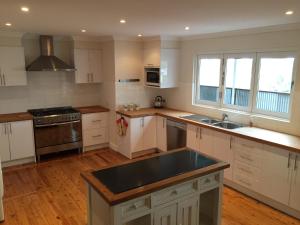 a kitchen with white cabinets and a black counter top at Molly's on Mount View - Walk to 3 Cellar Doors in Cessnock