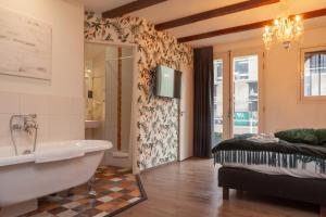 a bathroom with a tub and a bed and a television at Kings Inn City Hotel Alkmaar in Alkmaar
