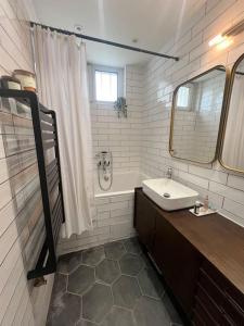 La salle de bains blanche est pourvue d'un lavabo et d'un miroir. dans l'établissement Le 81 - Paris & Versailles, jardin et parking, à Clamart