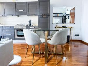 a kitchen with a glass table and two white chairs at Luxury White Apartment BGY - Orio al Serio Airport in Zanica