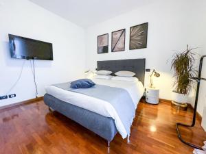 a bedroom with a bed and a flat screen tv at Luxury White Apartment BGY - Orio al Serio Airport in Zanica