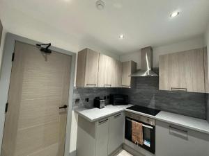 a kitchen with wooden cabinets and a stove top oven at Serviced Ensuite Double Room - Near Greenwich Park - The O2 Arena - Nearby Transport Links to Central London - New Cross Station - Lewisham SE14 in London