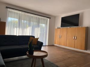 uma sala de estar com um sofá, uma televisão e uma mesa em Tölgyes Apartmanház em Szeged