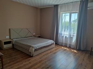 Будинок де є басейн та дві бесідки في كييف: غرفة نوم بسرير ونافذة كبيرة