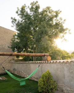 MedionaにあるCan Óscar Rural Casa con piscina y barbacoa ideal para famíliasの壁の隣の庭の緑のハンモック