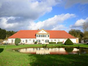 a large white house with a red roof and a pond at Holiday apartment Kettler in Sassenberg