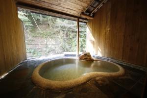 a large bath tub in a room with a window at Hinatamikan in Nakanojo
