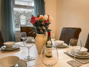 a table with a vase of flowers and wine glasses at The Victoria - Quaint Victorian Home With Free Parking in York