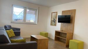 a living room with a couch and a television at Ferienwohnungen zum Stern in Bühlertann