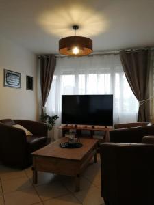 a living room with a flat screen tv and a table at Médina maison 4 chambres 100m2 in Beuvrages