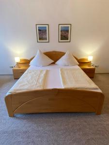 コッヘムにあるホテル ヒーロニミのランプ2つが備わる客室の大型木製ベッド1台