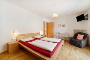 a bedroom with a large bed and a chair at Fröhlichhof Wohnung Pink Lady in Lagundo