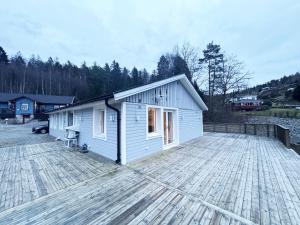 Nice cottage outside Munkedal with sea view في مونكيدال: مبنى أبيض صغير على سطح خشبي