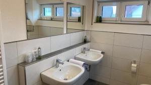 La salle de bains est pourvue de 2 lavabos et d'un miroir. dans l'établissement Ferienwohnungen zum Stern, à Bühlertann